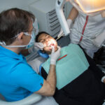 man-examining-oral-cavity-young-african-american-man-working-dental-clinic-with-assistant